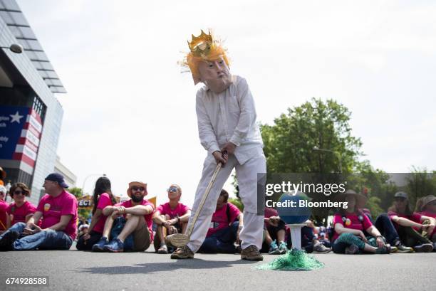 Demonstrator wearing a mask in the likeness of U.S. President Donald Trump prepares to swing a golf club at a globe during the People's Climate...