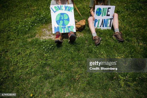 Demonstrators sit and hold signs before the start of the People's Climate Movement March in Washington, D.C., U.S., on Saturday, April 29, 2017....