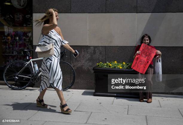 Demonstrators holds a sign as a pedestrian walks by during the People's Climate Movement March in Washington, D.C., U.S., on Saturday, April 29,...