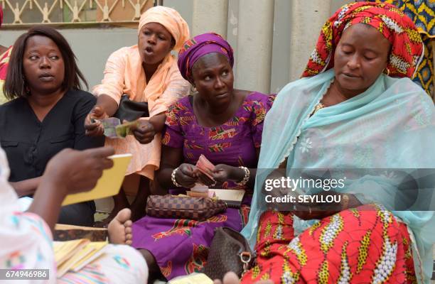 Senegalese women sit on a mat in a home in Grand-Mbao, on March 9 as they count and register the money put in by members for a "cagnotte de la...