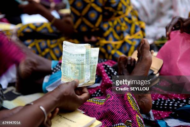 Senegalese woman holds paper money at a home in Grand-Mbao, on March 9 as she and other register the money put in by members for a "cagnotte de la...