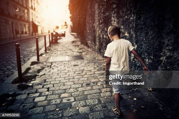 sad boy walking sidewalk at paris montmartre - street child stock pictures, royalty-free photos & images