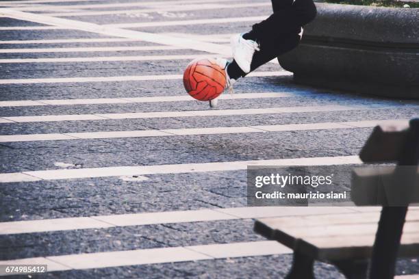 young man running with soccer ball in street - abilità - fotografias e filmes do acervo