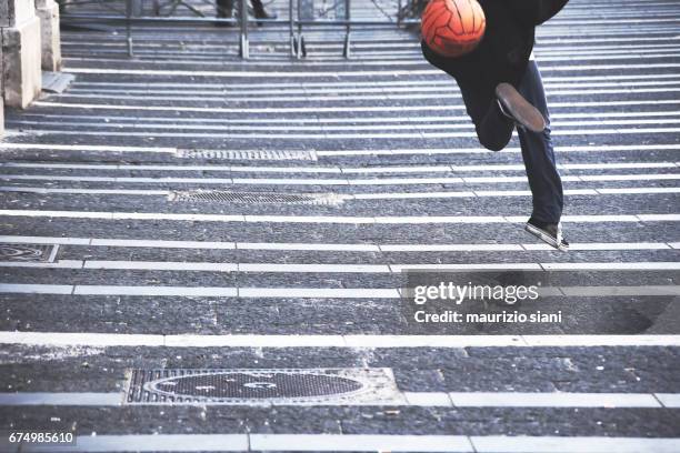 young man playing with soccer ball on road - pallone da calcio stockfoto's en -beelden