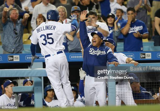 Cody Bellinger of the Los Angeles Dodgers is greeted by manager Dave Roberts as he returns to the dugout after hitting a solo home run in the ninth...