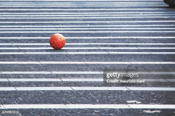 a soccer ball in the street - pavimento stockfoto's en -beelden