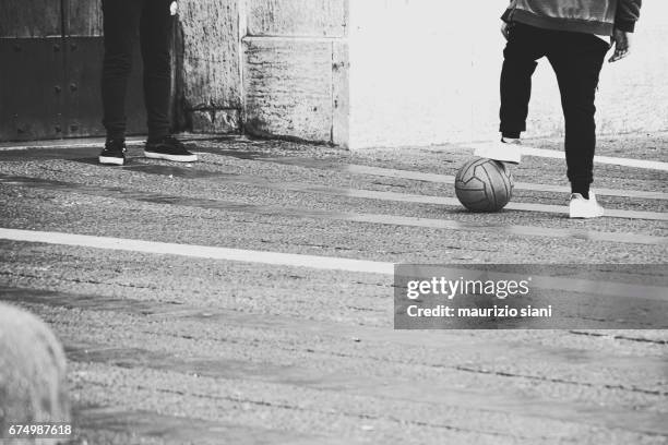 children playing with soccer ball on urban street - sfida stock pictures, royalty-free photos & images