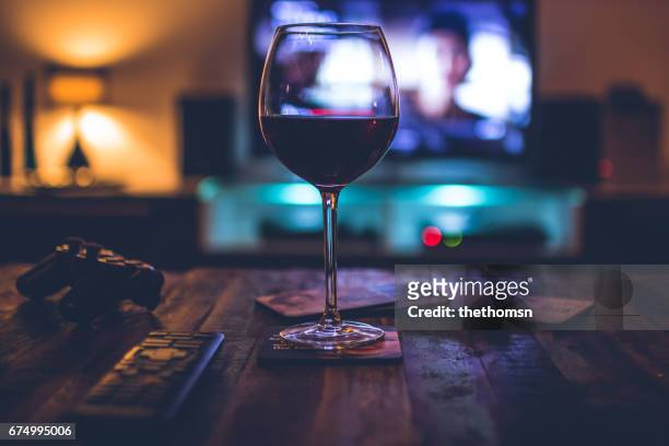 dark indoor scene with a redwine filled glass in front of a tv - betrunken stock pictures, royalty-free photos & images