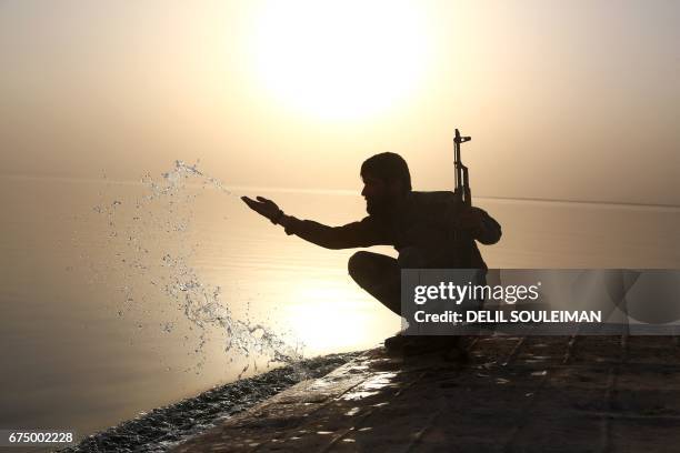 Member of the US-backed Syrian Democratic Forces , made up of an alliance of Arab and Kurdish fighters, splashes water at the Lake Assad, an enormous...