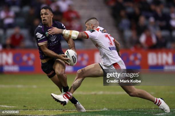Will Chambers of the Storm passes as he is tackled by Joel Thompson of the Dragons during the round nine NRL match between the St George Illawarra...