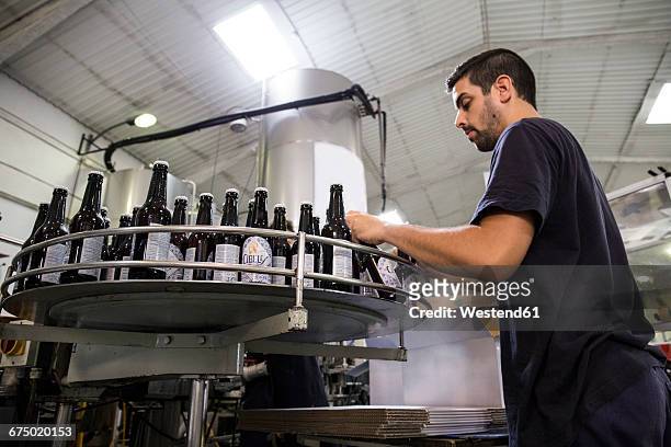 man working in beer bottling plant - bierflaschen fließband stock-fotos und bilder