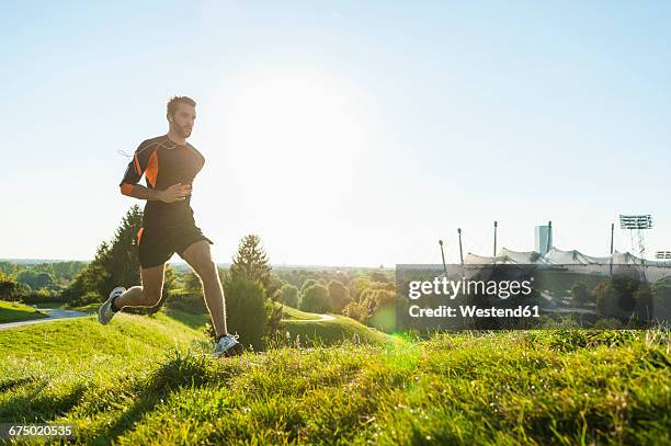 man running on meadow in park - olympiapark münchen stock-fotos und bilder