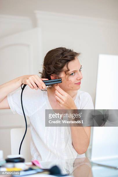 woman at home doing her hair with a hair straightener - flat iron stock pictures, royalty-free photos & images
