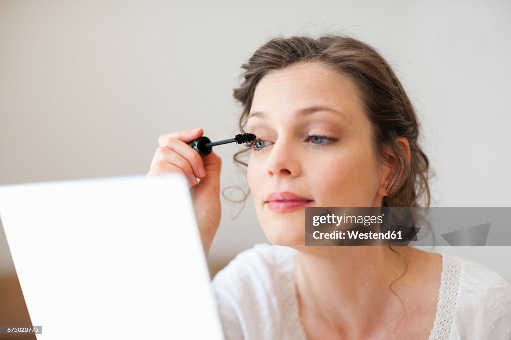 Woman looking in mirror applying mascara