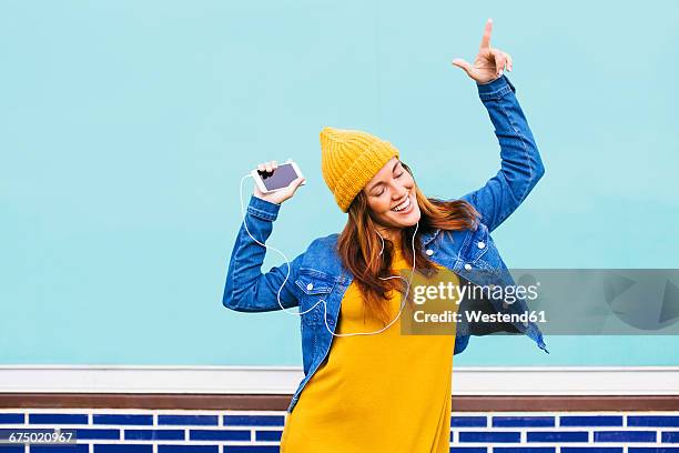 dancing young woman wearing yellow cap and dress - enjoyment phone stock pictures, royalty-free photos & images