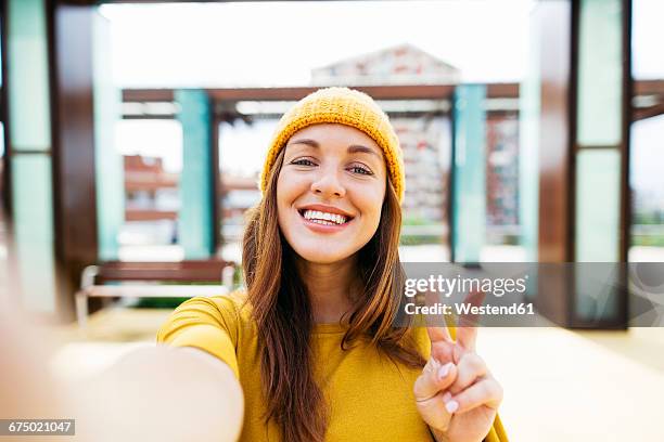 portrait of smiling young woman wearing yellow clothes taking selfie - autofoto fotografías e imágenes de stock