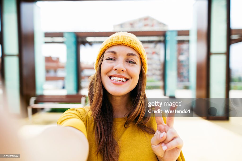 Portrait of smiling young woman wearing yellow clothes taking selfie