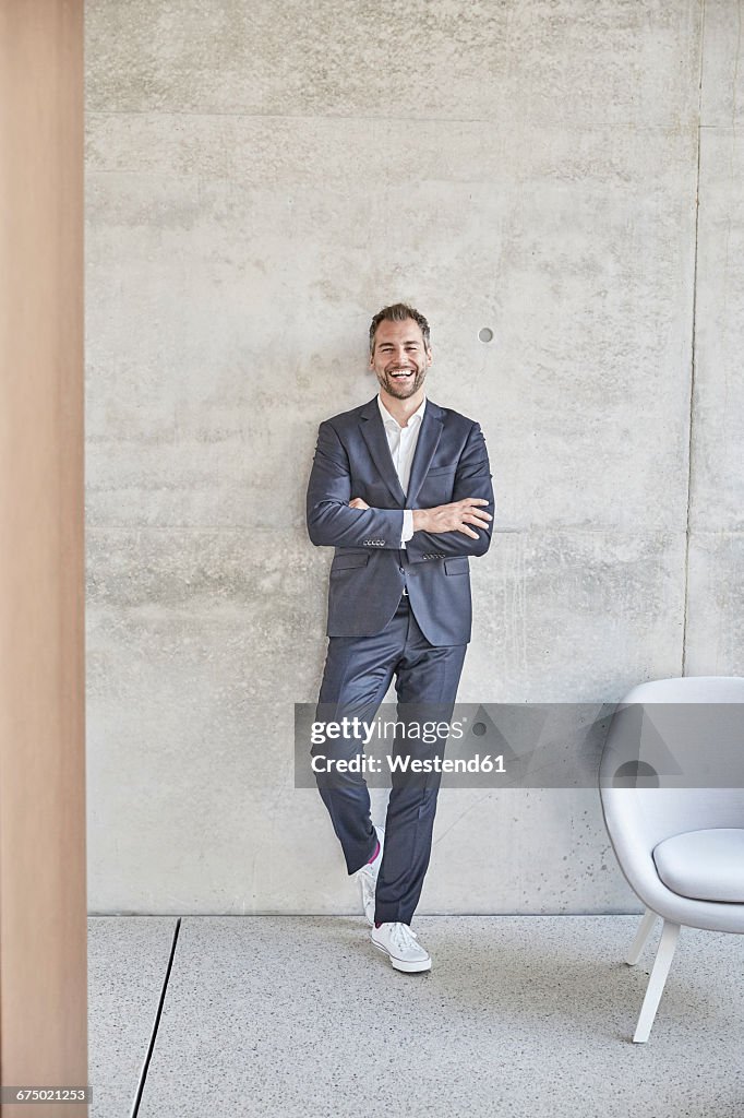 Laughing businesssman standing at concrete wall