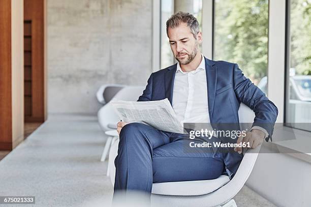 businesssman sitting on chair reading newspaper - news 2016 stock-fotos und bilder