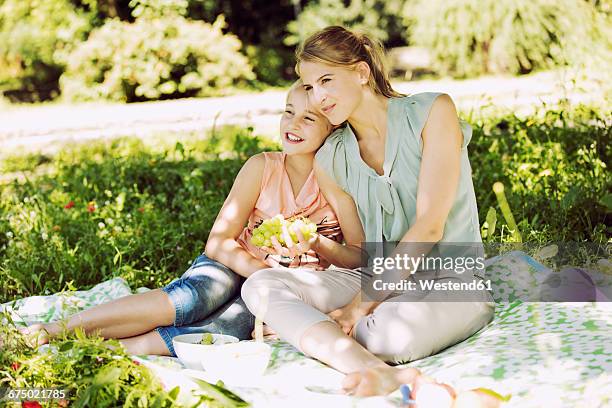 girl and young woman sitting together on blanket in a park watching something - niece fotografías e imágenes de stock