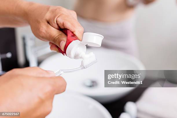 man's hands applying toothpaste on toothbrush, close-up - zahnpasta stock-fotos und bilder