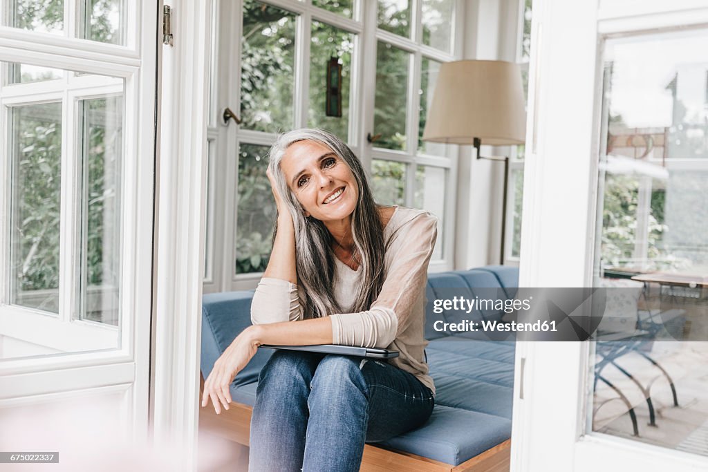 Smiling woman sitting on lounge in winter garden