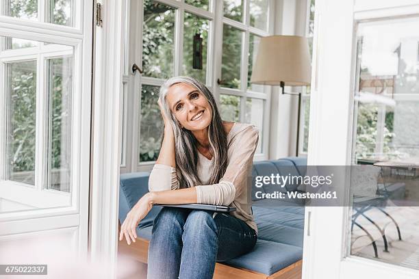 smiling woman sitting on lounge in winter garden - beautiful woman gray hair stock pictures, royalty-free photos & images