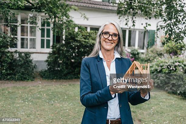smiling businesswoman with architectural model in the garden - architekturmodell stock-fotos und bilder