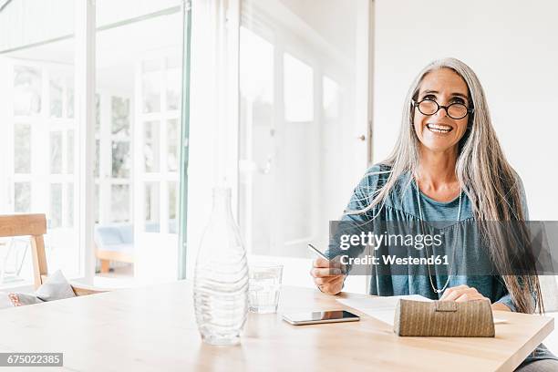 portrait of woman sitting at table writing down something - water glasses ストックフォトと画像
