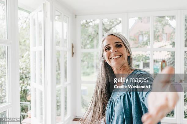 portrait of smiling woman inviting viewer in her winter garden - idyllic stock-fotos und bilder