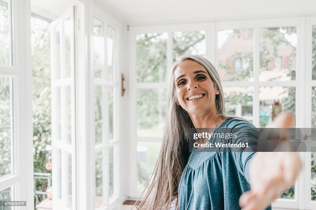 Portrait of smiling woman inviting viewer in her winter garden