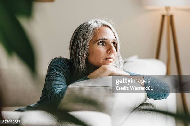 pensive woman on the couch at home - beschouwing stockfoto's en -beelden