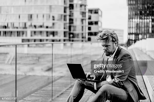 businessman sitting on bridge using laptop - schwarz weiss stock-fotos und bilder