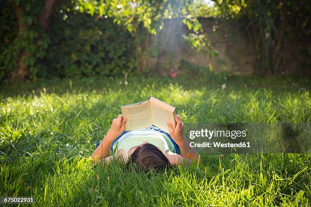 girl reading book on a meadow - lying on back ストックフォトと画像