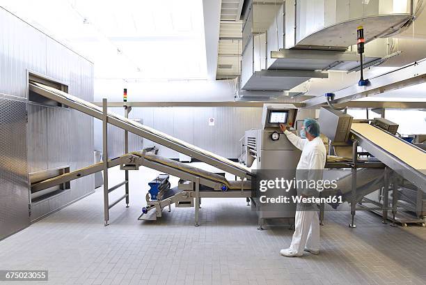 worker operating machine in an industrial bakery - voedsel-verwerkingsbedrijf stockfoto's en -beelden