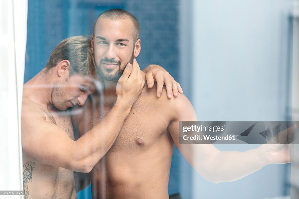 Gay couple embracing at window