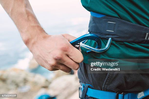 close-up of climber placing a carabiner in his climbing harness - karabijnhaak stockfoto's en -beelden