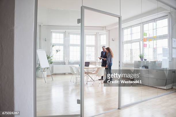 businessman and woman standing in bright office - businessman distance window ストックフォトと画像