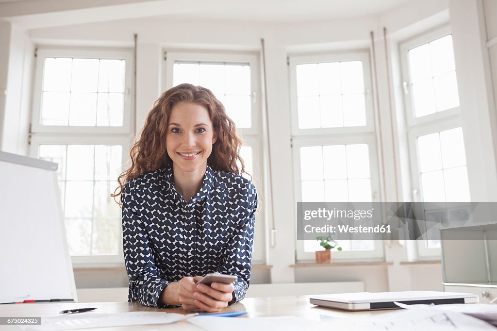 Portrait of smiling woman at desk in office