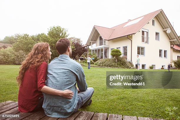 couple in garden looking at house - eigenheim familie stock-fotos und bilder