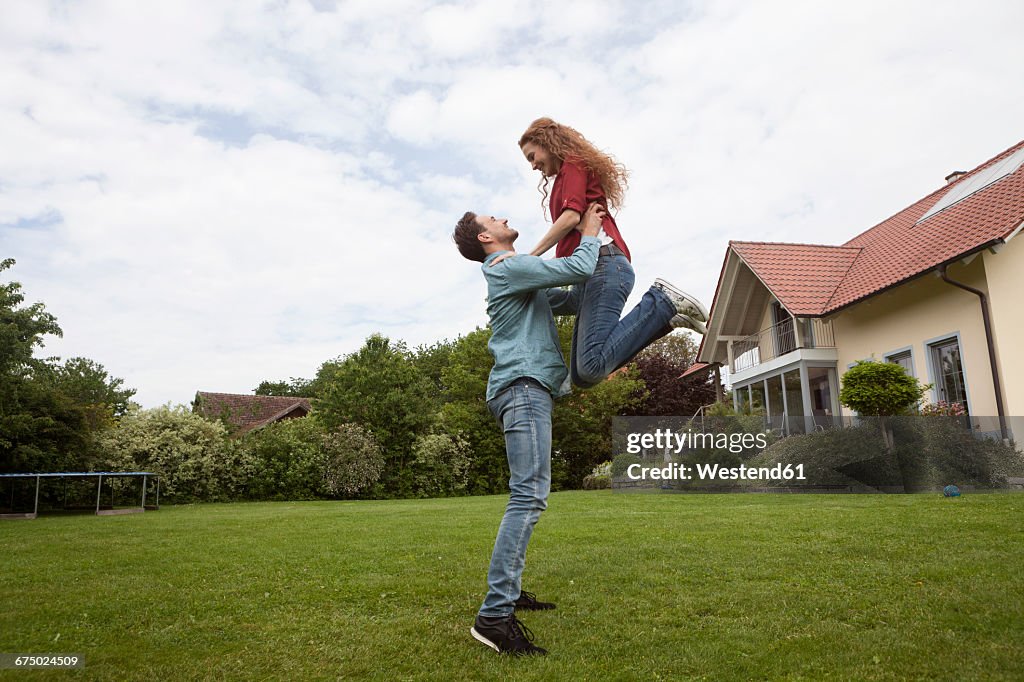 Happy man lifting up woman in garden