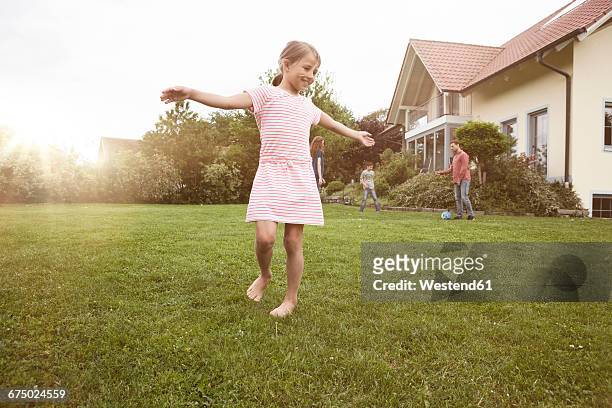 girl dancing in garden with family in background - junge barfuß stock-fotos und bilder
