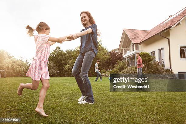 mother and daughter dancing in garden with family in background - children dancing outside stockfoto's en -beelden