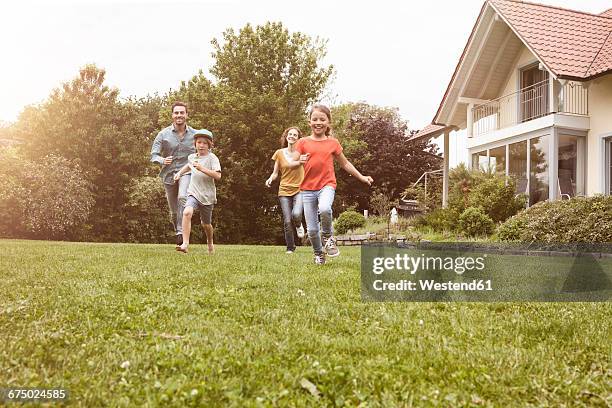 carefree family running in garden - einzug gegenlicht stock-fotos und bilder