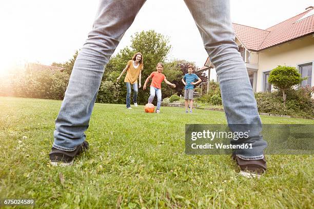 family playing football in garden - legs spread stock-fotos und bilder