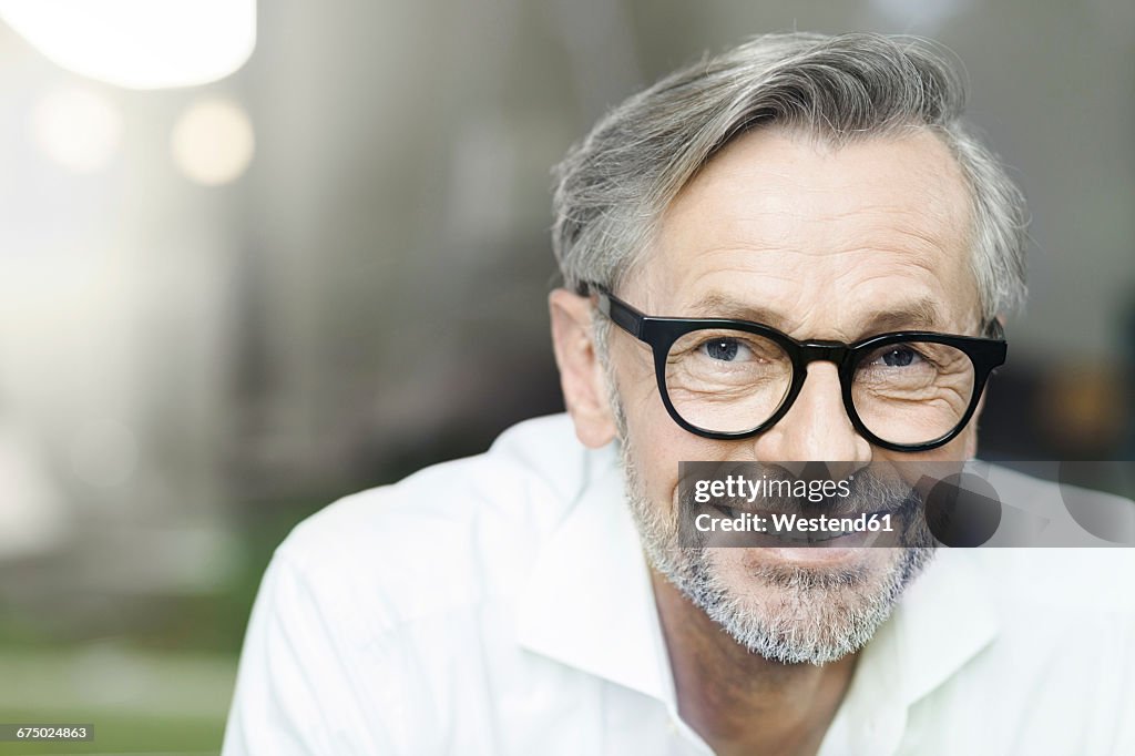 Portrait of smiling man with grey hair and beard wearing spectacles