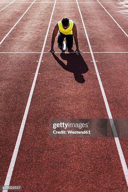runner on tartan track in starting position - estadio de atletismo fotografías e imágenes de stock