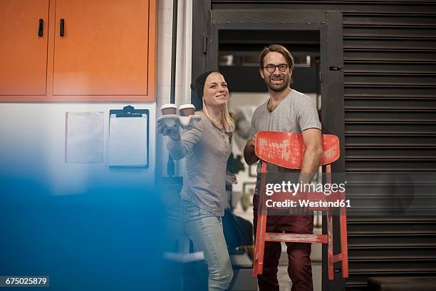 man and woman with coffee to go and chair leaving workshop - man hauling stock pictures, royalty-free photos & images