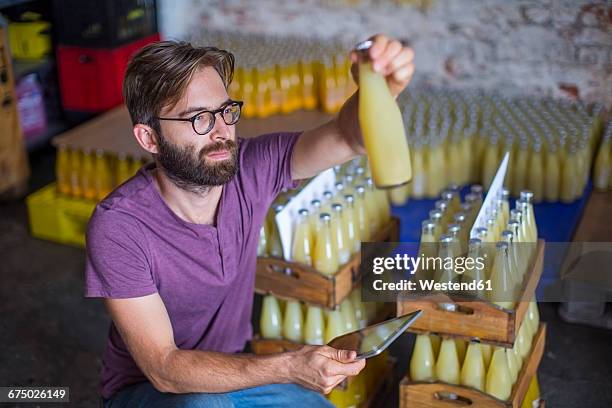 man checking stock of juice bottles in warehouse - bottling plant stock pictures, royalty-free photos & images