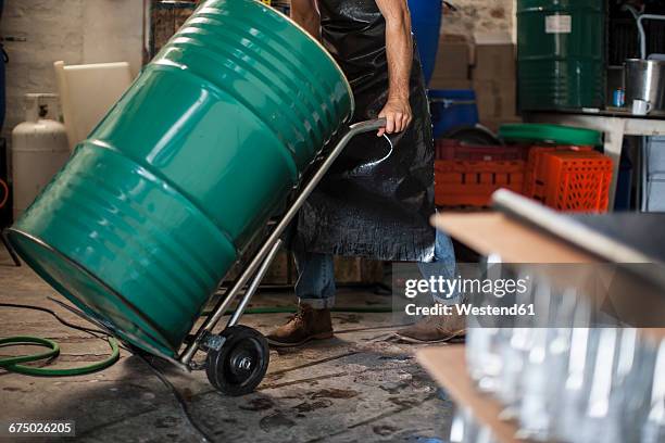 man pushing metal container in a warehouse - drum container stock-fotos und bilder